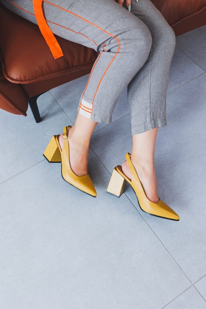 A slender woman sits in a chair in high-heeled sandals. Collection of summer women's shoes