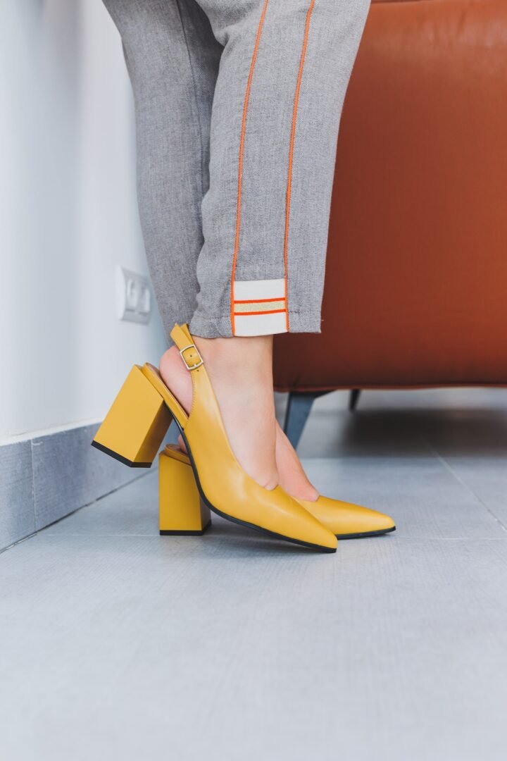A slender woman sits in a chair in high-heeled sandals. Collection of summer women's shoes